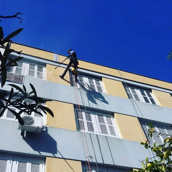Profissional da Certa executando pintura de fachada predial em altura